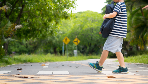 little kid crossing street in pedestrian crosswalk